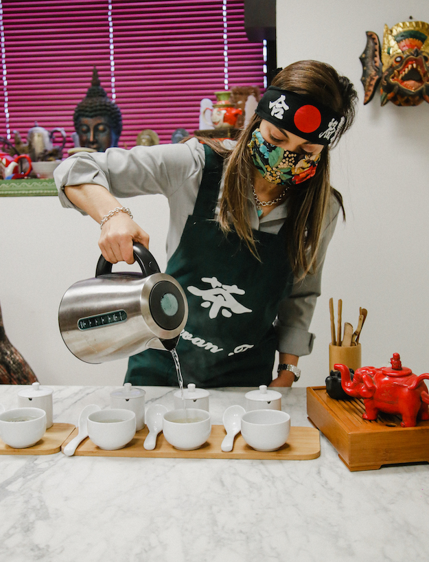 Alondra sirve varias tazas de té con delantal y mascarilla